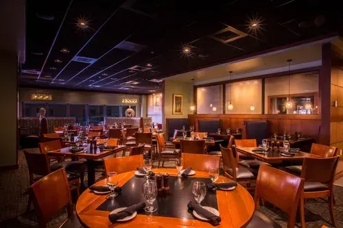 Upscale restaurant dining room with set tables, warm lighting, and wooden chairs