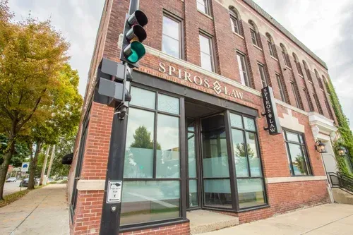 Corner brick storefront with large windows and green traffic light on a city sidewalk