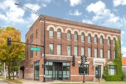 Brick corner commercial building with large windows and awnings on a sunny street intersection