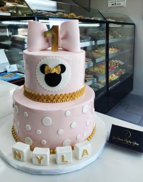 A pink cake with polka dots and a mickey mouse on it