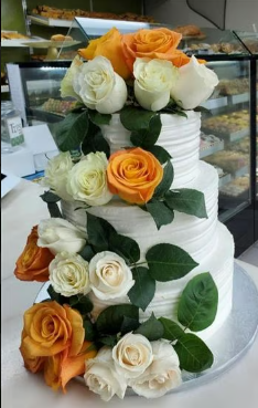 A white cake with orange and white roses on it