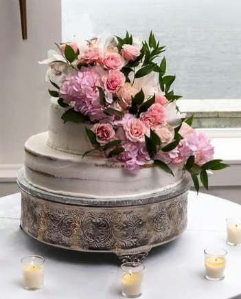 A wedding cake with pink flowers and candles on a table.