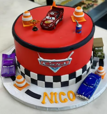 A cake with cars on it and the name nico on it