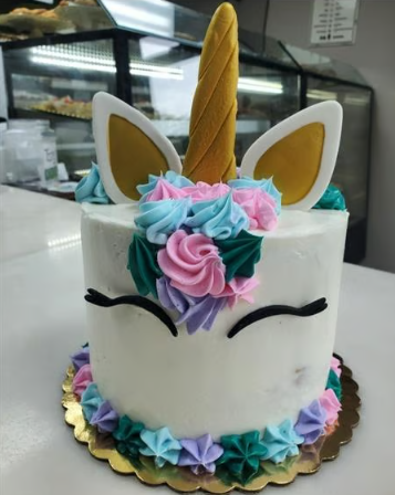 A white cake with a unicorn face on it