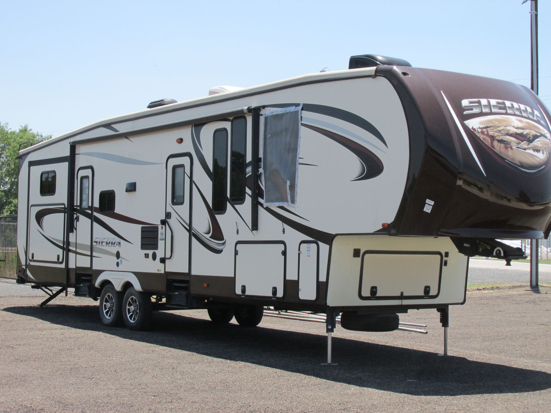 A Sierra fifth-wheel recreational vehicle parked on a gravel lot under a clear sky.
