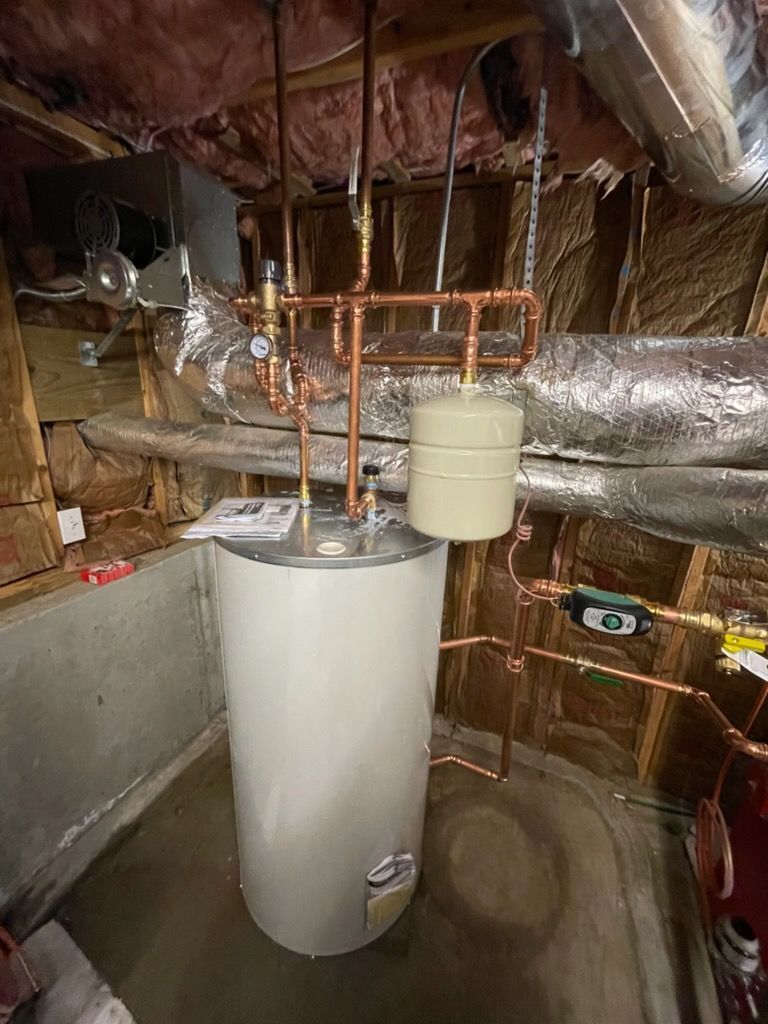 Water heater with copper pipes in a basement, pressure tank, and insulation.