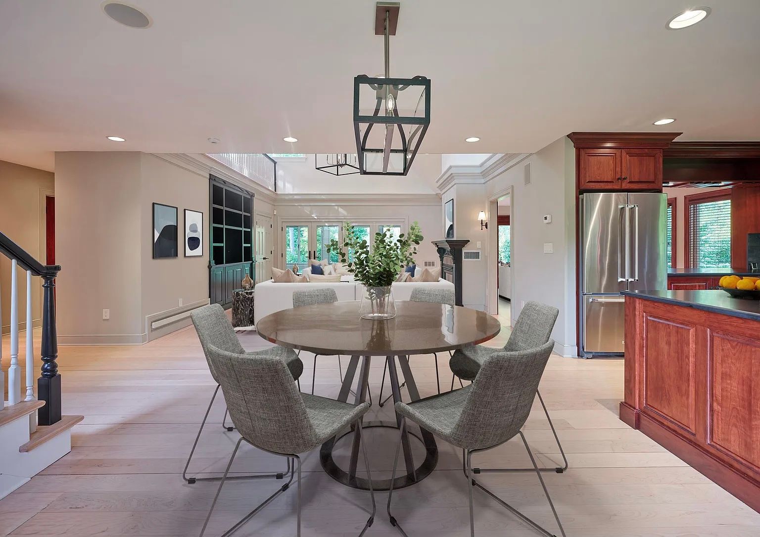 Dining room with round table, four chairs, and kitchen access. Light wood floors, neutral walls.