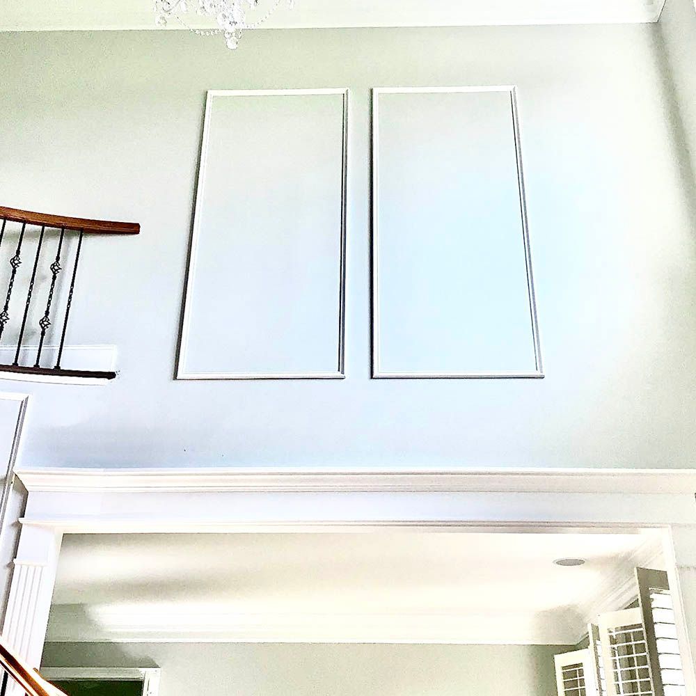 Two tall, rectangular, light-colored panels hang on a high wall above a doorway.