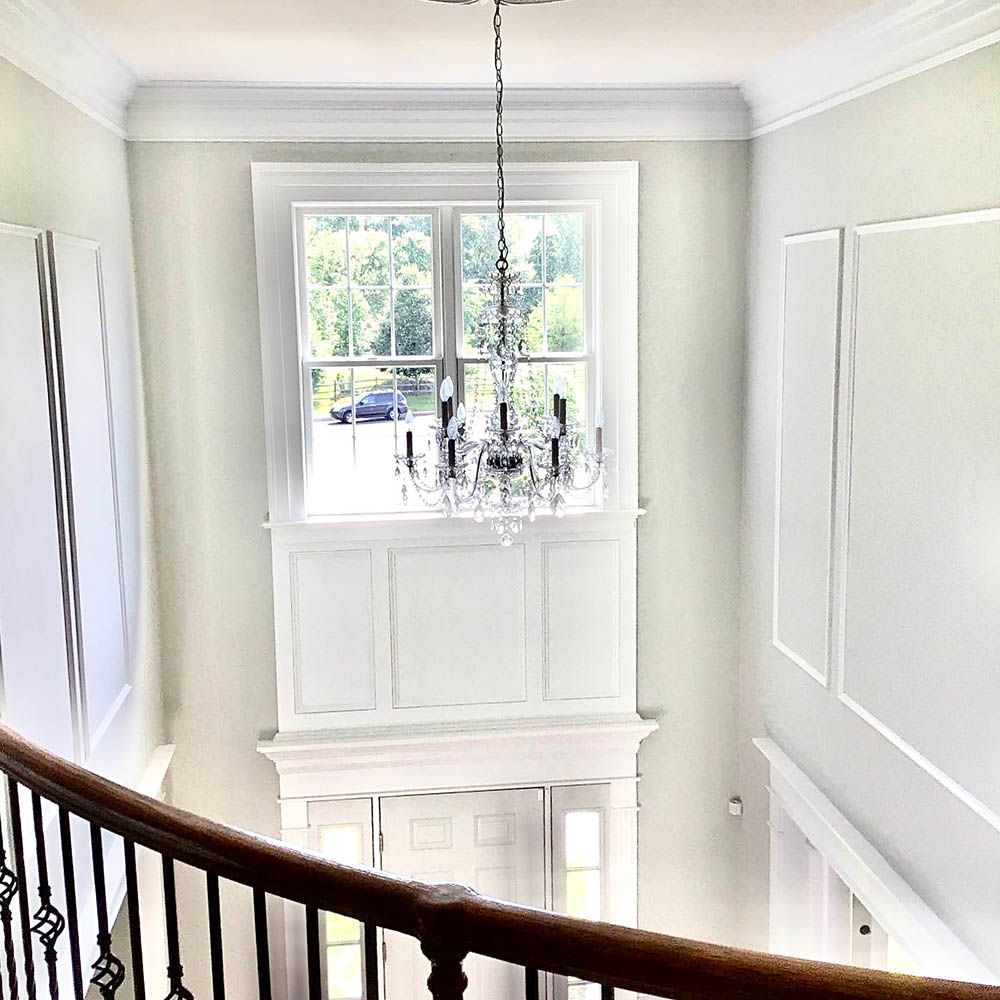 Interior view of a two-story foyer with a chandelier, window, and curved staircase.