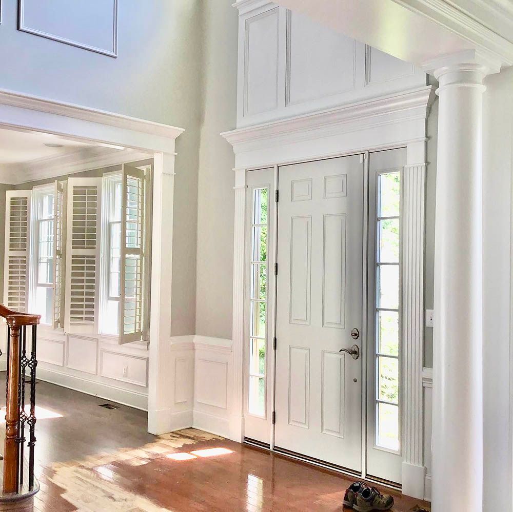 White interior with double doors, sidelights, and detailed trim; hardwood floors.