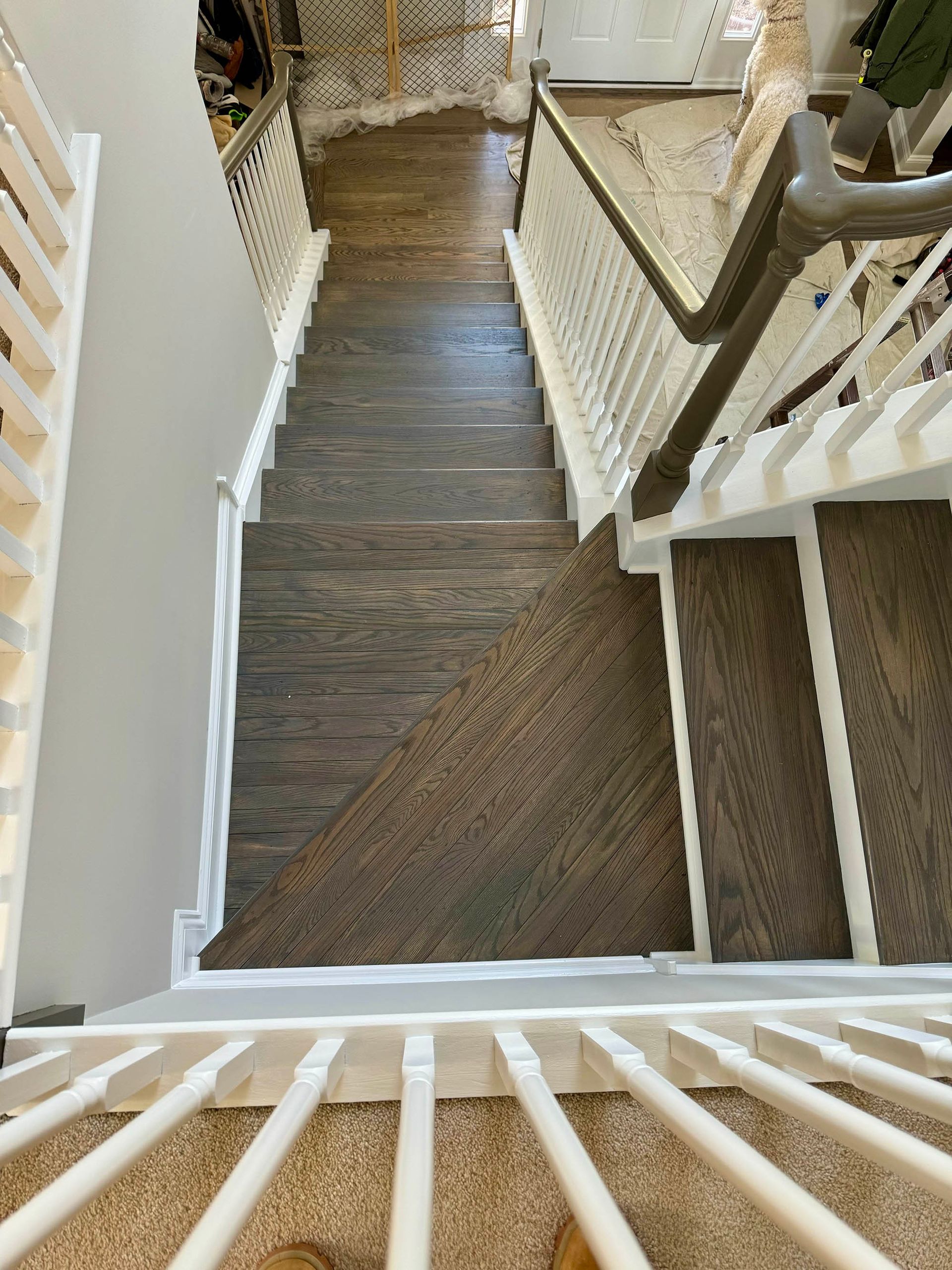 Staircase with dark wood treads and white banisters. A carpet runner covers the center.