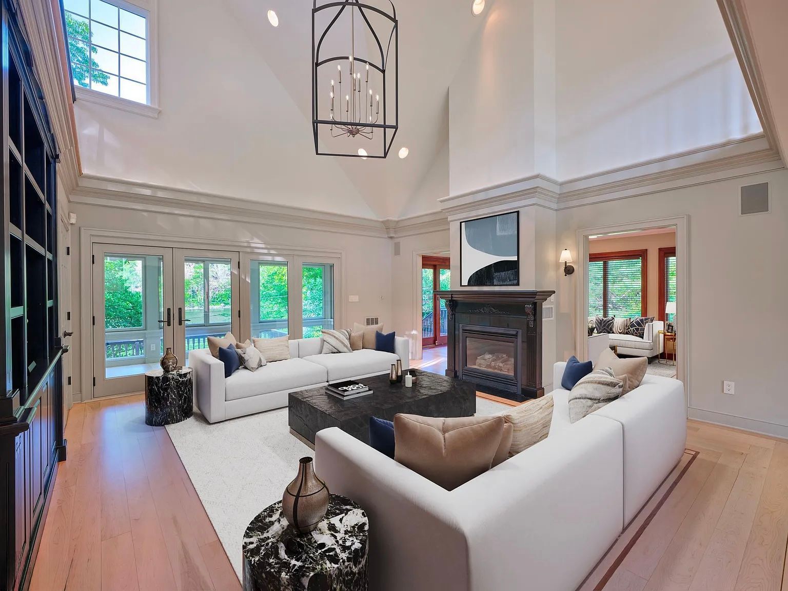 Living room with white sofas, fireplace, and large windows.