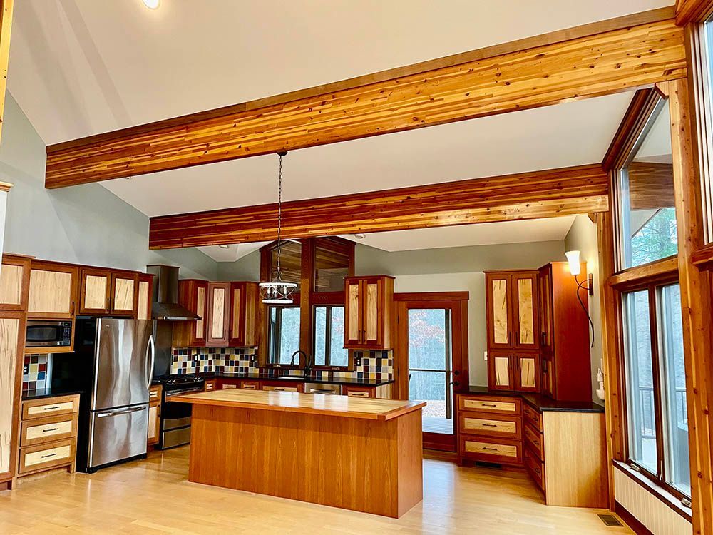 Spacious kitchen with wood beams, cabinetry, island, and stainless steel appliances. Bright, airy, and inviting space.