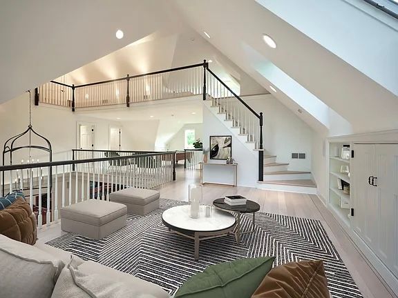 Spacious, white, two-story living room with stairs, a loft, and modern furniture.