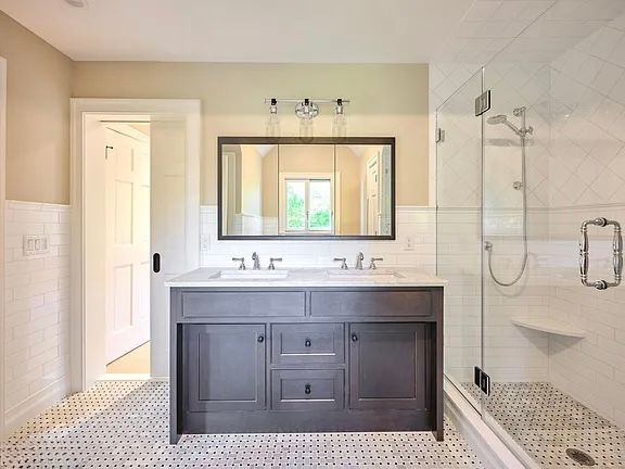 Bathroom with gray vanity, white tile floor, shower, and large mirror.