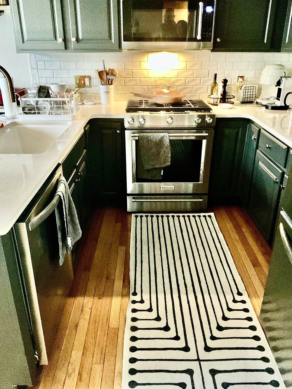 Kitchen with dark cabinets, stainless steel appliances, and a geometric rug.