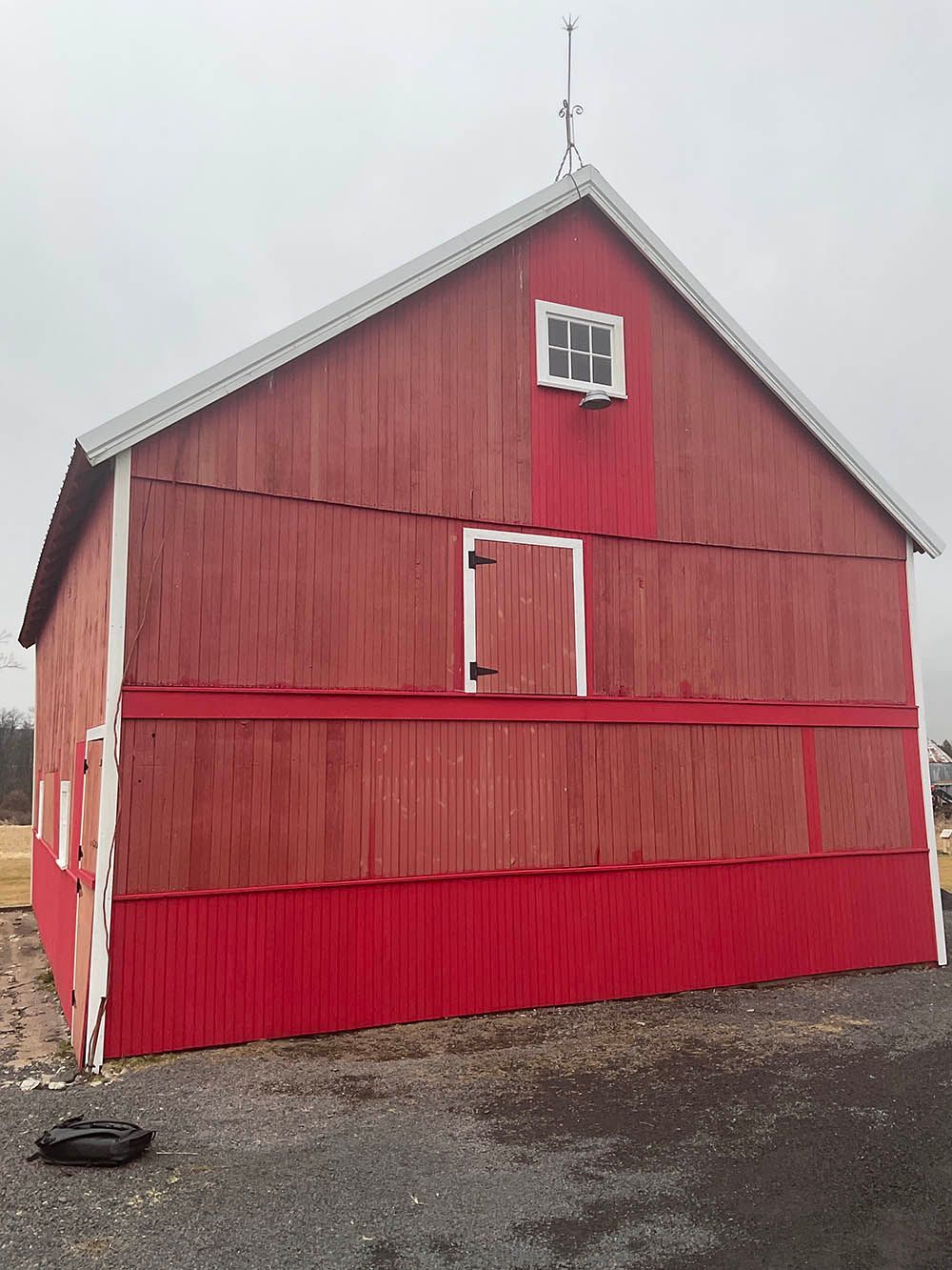 Red wooden barn on a gray day; white trim and small upper window.