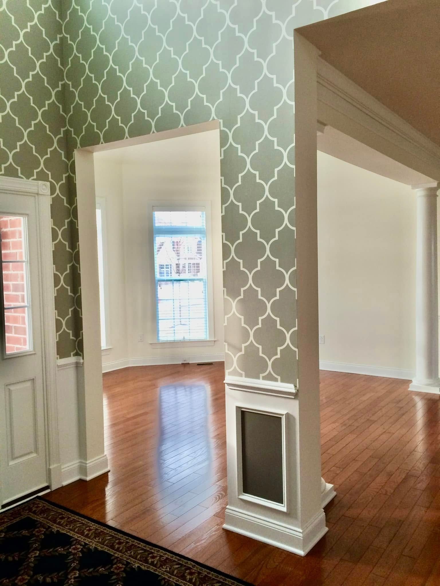 Interior with patterned wallpaper, hardwood floors, and white trim.