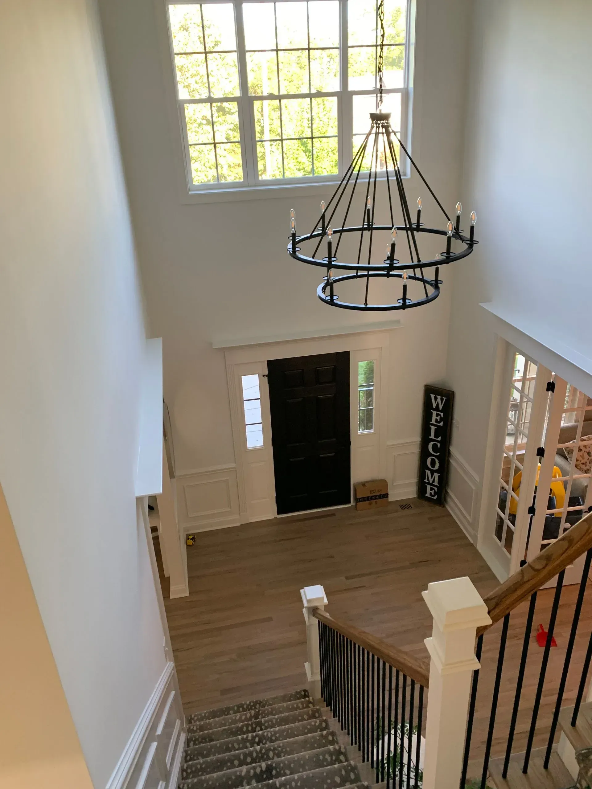 Looking down at a two-story foyer with a chandelier, front door, and staircase.