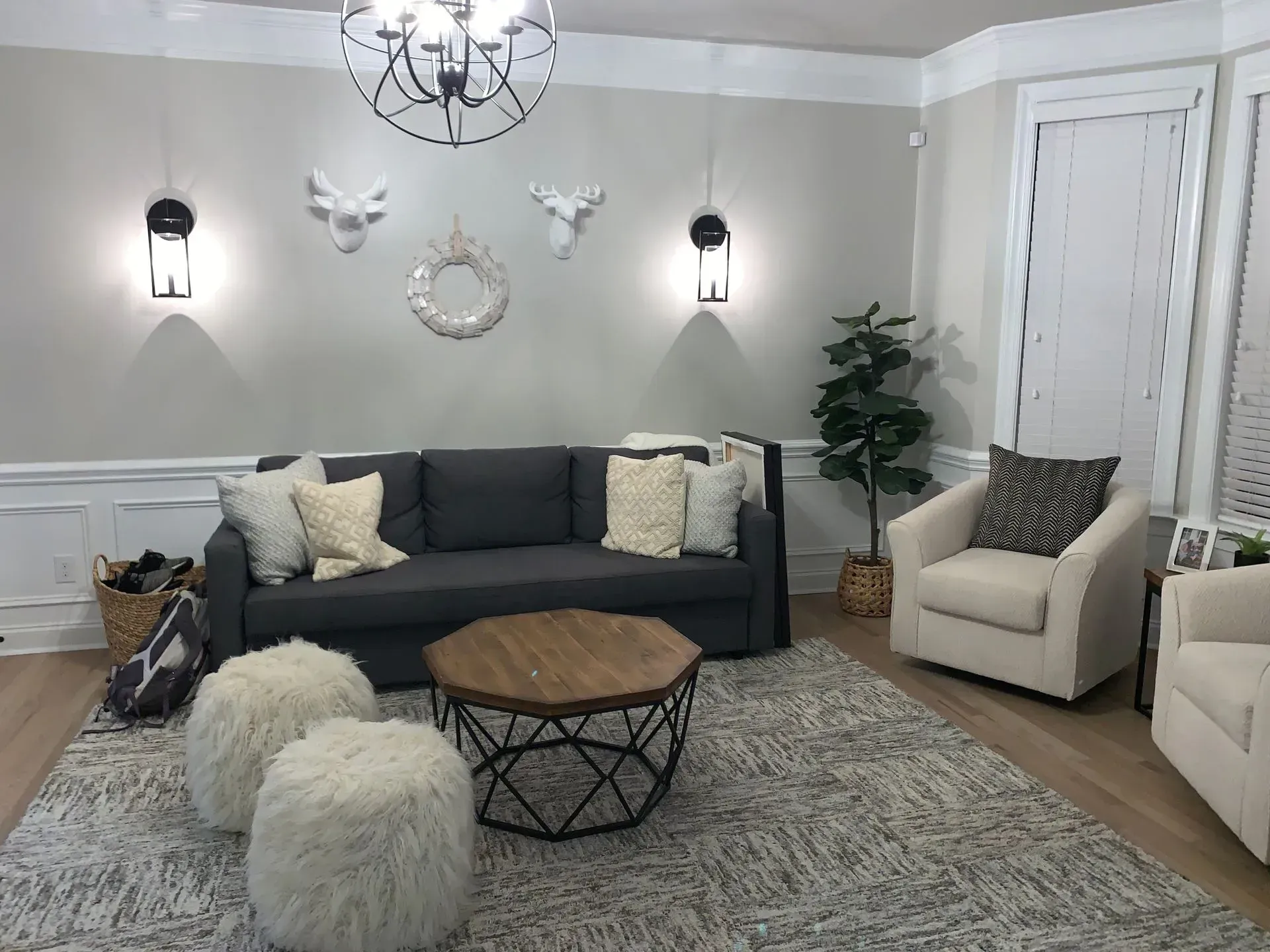 Living room: Gray couch, light chairs, wood coffee table, white wall decor, and a gray rug.
