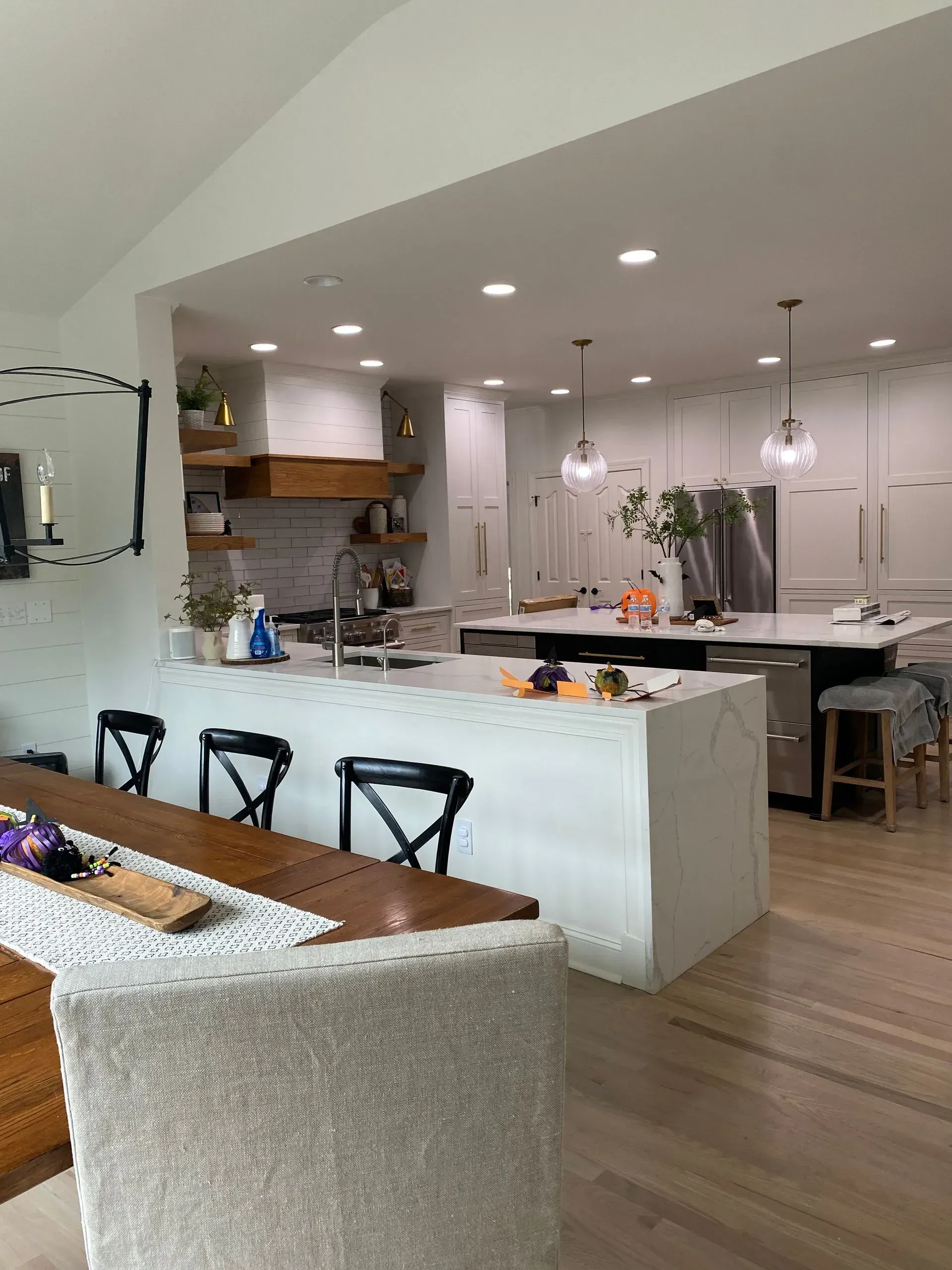 Spacious modern kitchen with white counters, island, and dining table; chairs, light wood floor.