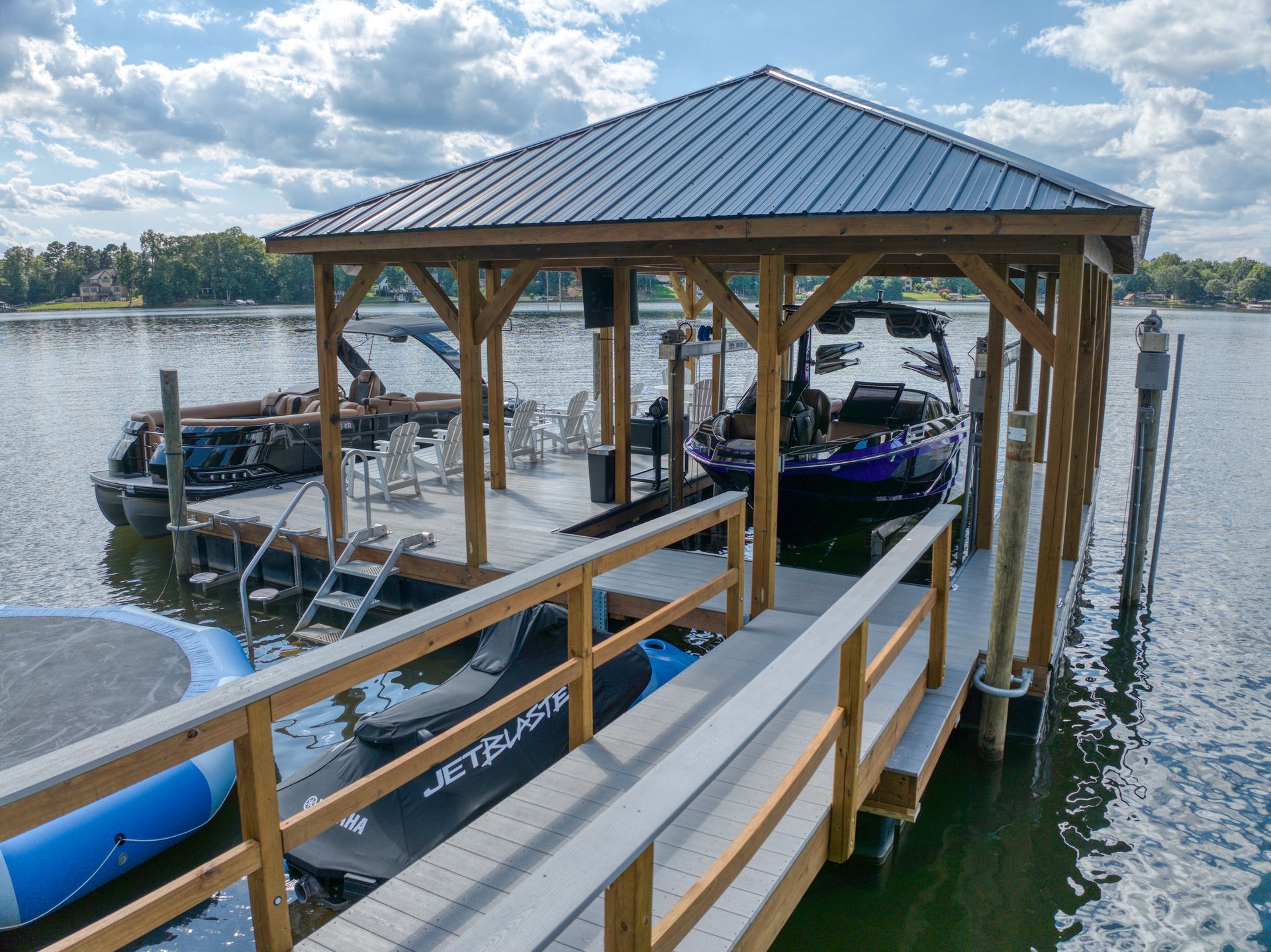 Wooden dock with boat shelter, containing a boat, chairs, and a swim platform on a lake.