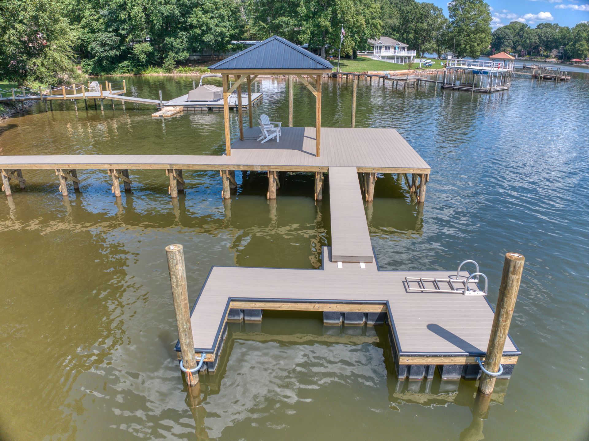 Dock extending into calm lake with a gazebo, and two boat slips; sunny day.