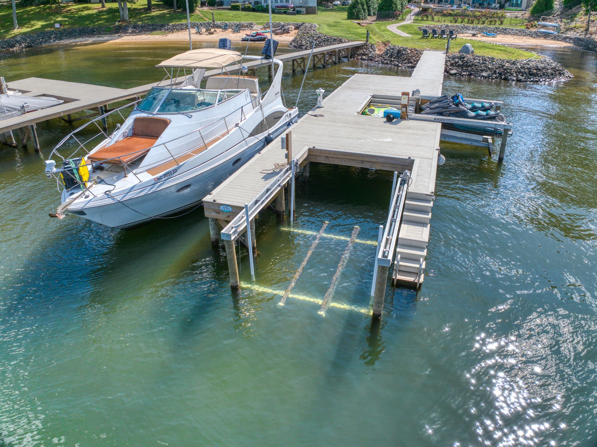 Boat docked next to a wooden pier with boat lift over a lake.