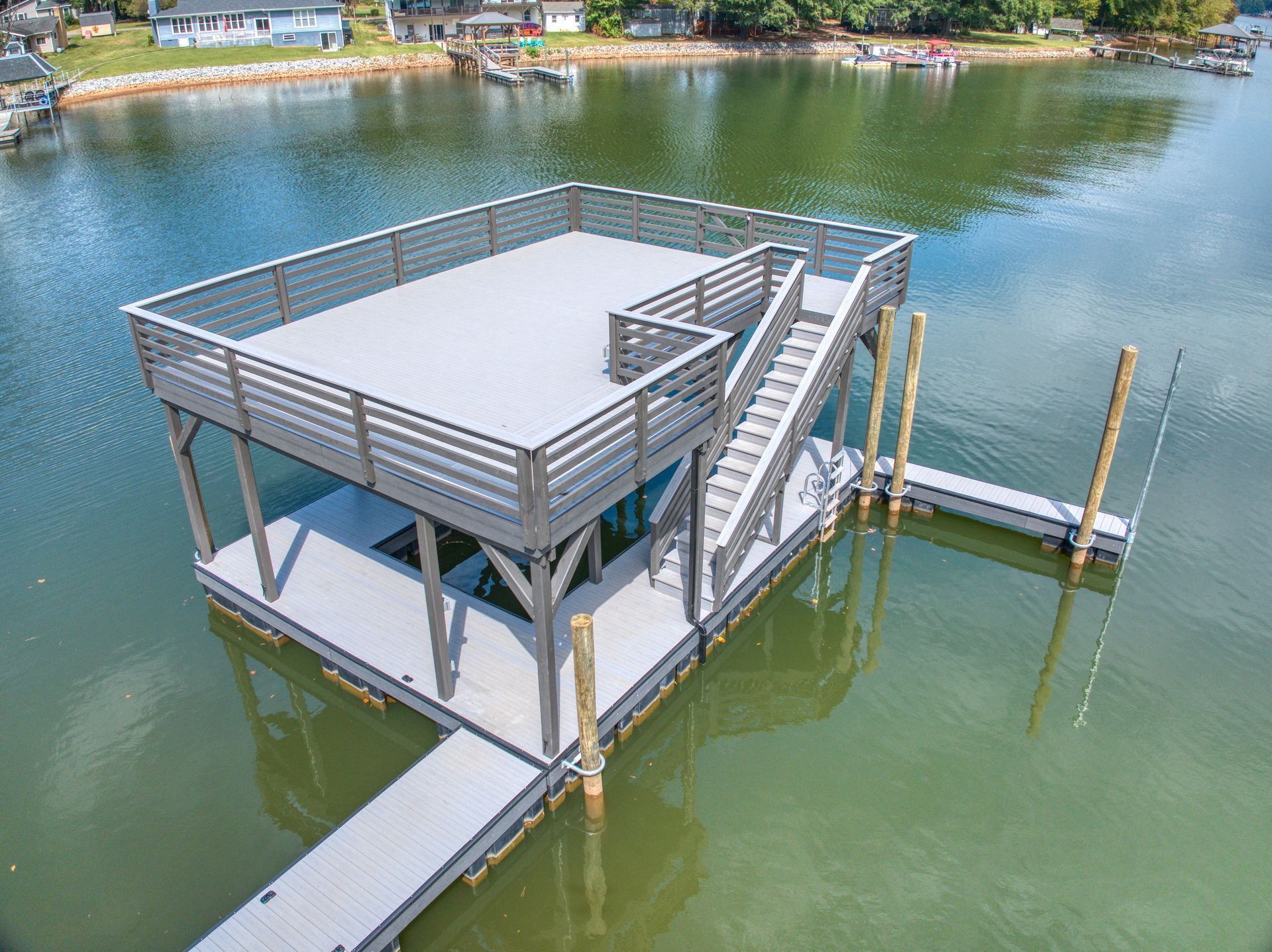 Lake dock with a trampoline-like netting for water access, under a cloudy sky.