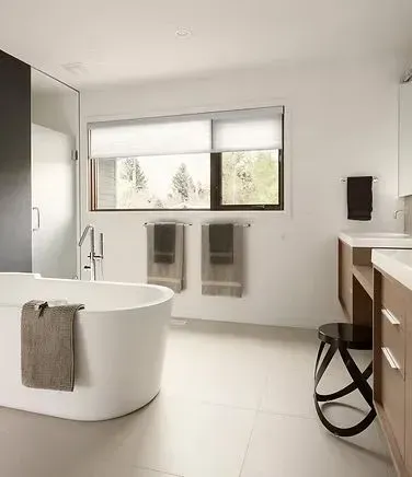 Modern bathroom with a white tub, natural light, and wooden cabinets.