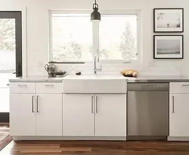 White kitchen with farmhouse sink, stainless steel dishwasher, and window.