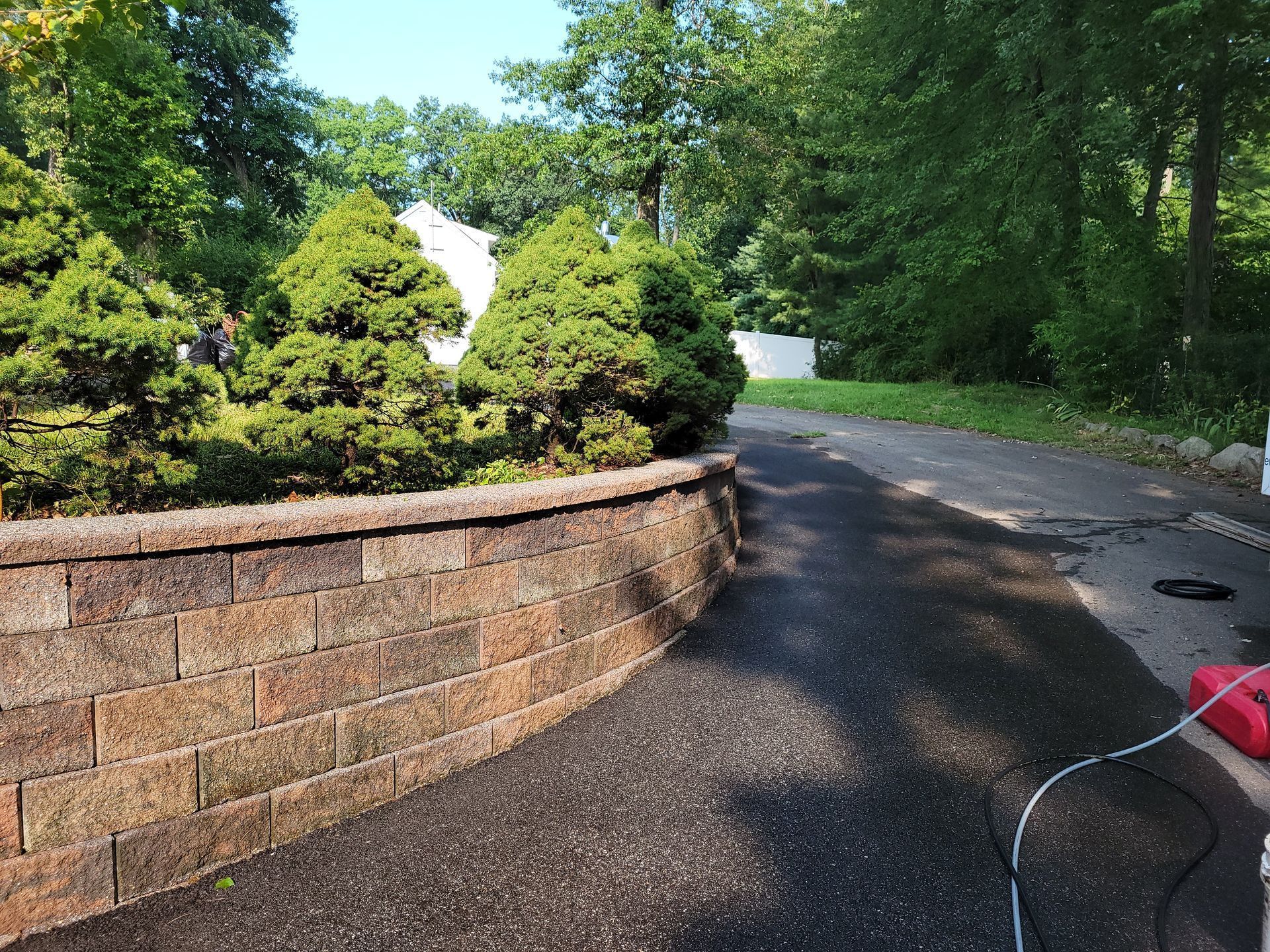 A brick wall along the side of a road with trees in the background.