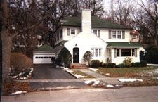 A large white house with a green roof and a garage.