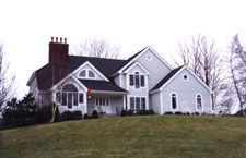 A large white house is sitting on top of a grassy hill.