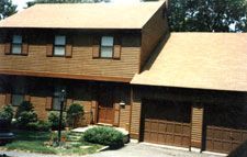 A house with two garage doors and a car parked in front of it.