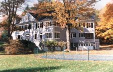 A large house with a lot of windows is surrounded by trees and grass.