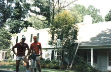 Three men are standing in front of a house.