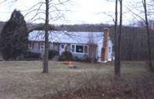 A house is sitting in the middle of a field surrounded by trees.