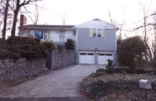 A large house with a stone wall and a driveway leading to it.