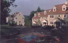 A red car is parked in front of a row of houses.