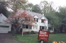 A house with a painting trailer parked in front of it.