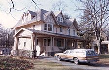 A car is parked in front of a large house.