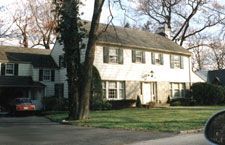 A large white house with a car parked in front of it.