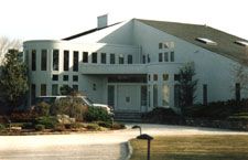 A large white house with a car parked in front of it.