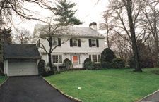 A large white house with a garage and a driveway in front of it.