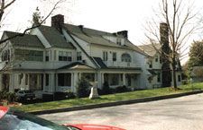 A large white house with a red car parked in front of it.