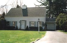 A white house with a garage and a driveway in front of it.