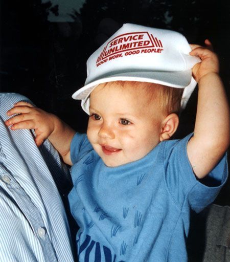 A baby wearing a hat that says service unlimited.