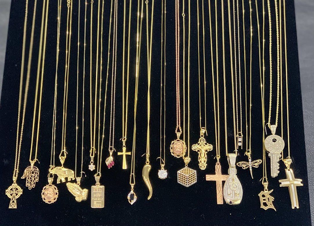 A bunch of gold necklaces with different pendants on them