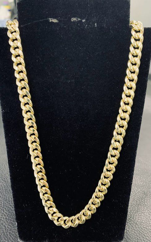 A gold chain is on a black mannequin.